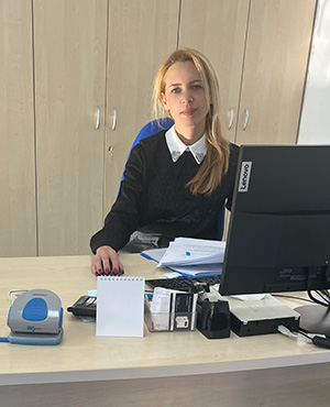 Natalie Popova, recruitment consultant, seated at a desk with a computer in an office environment.