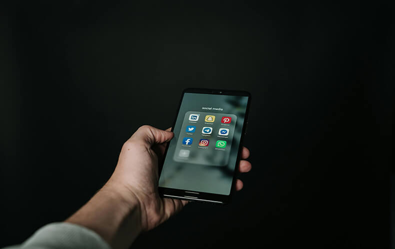 Strategic online presence portrayed by a hand holding a smartphone with prominent social media icons, aligning with the digital job hunting strategies highlighted in the Effective Job Hunting Strategies blog