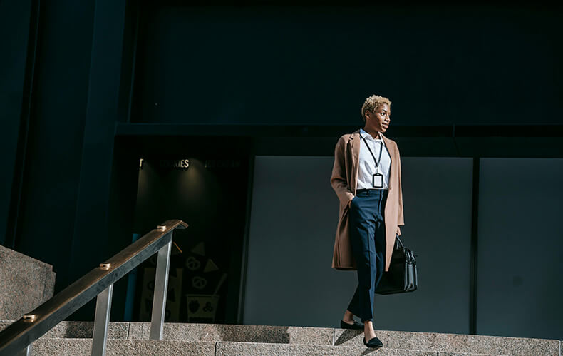 Visual representation of success with a confident woman standing proudly on stairs in front of a prominent business building. Symbolizes career achievement and the blend of tradition and innovation emphasized in the Effective Job Hunting Strategies blog